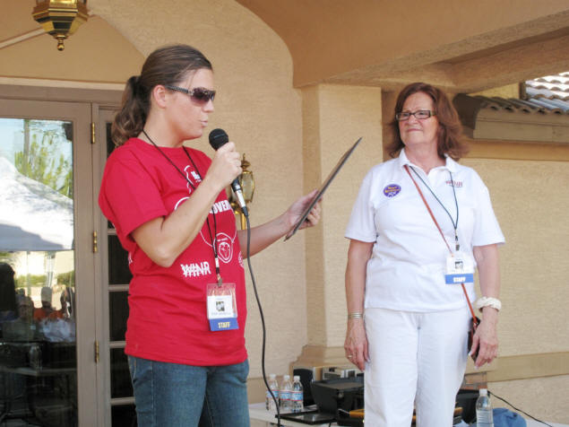 Jenny Cilwa passes an award to Patty Henderson, founder of WINR.