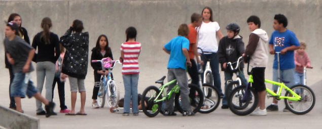 A crowd gathers around a fallen biker.