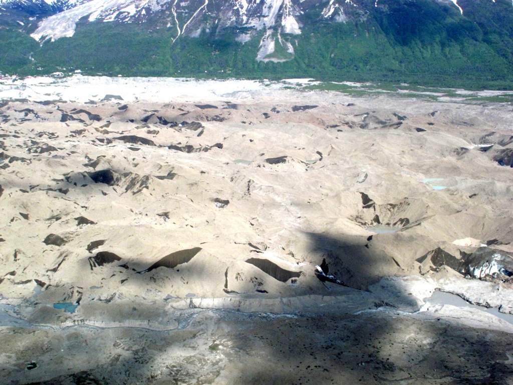 Hidden ice peaks out through breaks in the glacial silt.